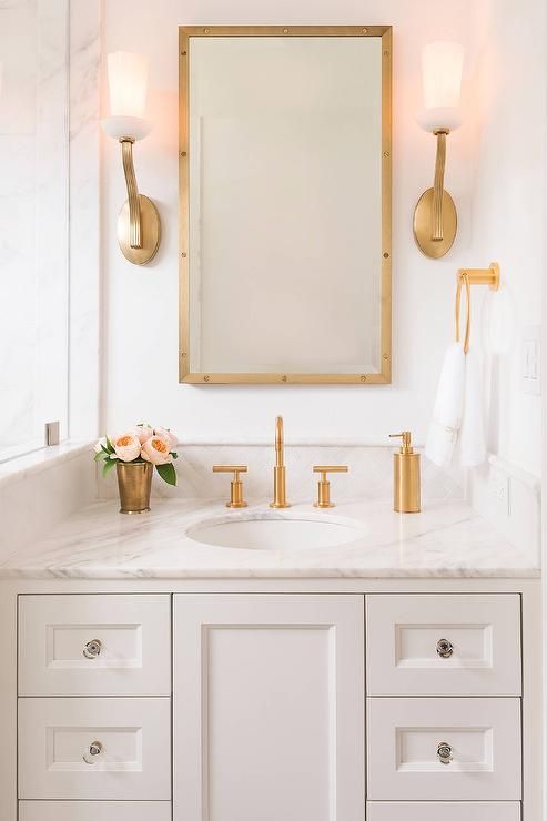 Gold fixtures on marble vanity with mirror and double sconces