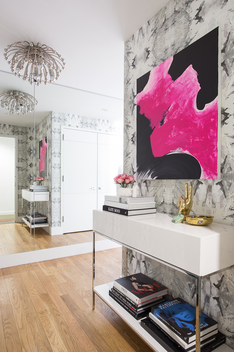 Entryway with white console table, pink artwork and silver pendant light via Homepolish