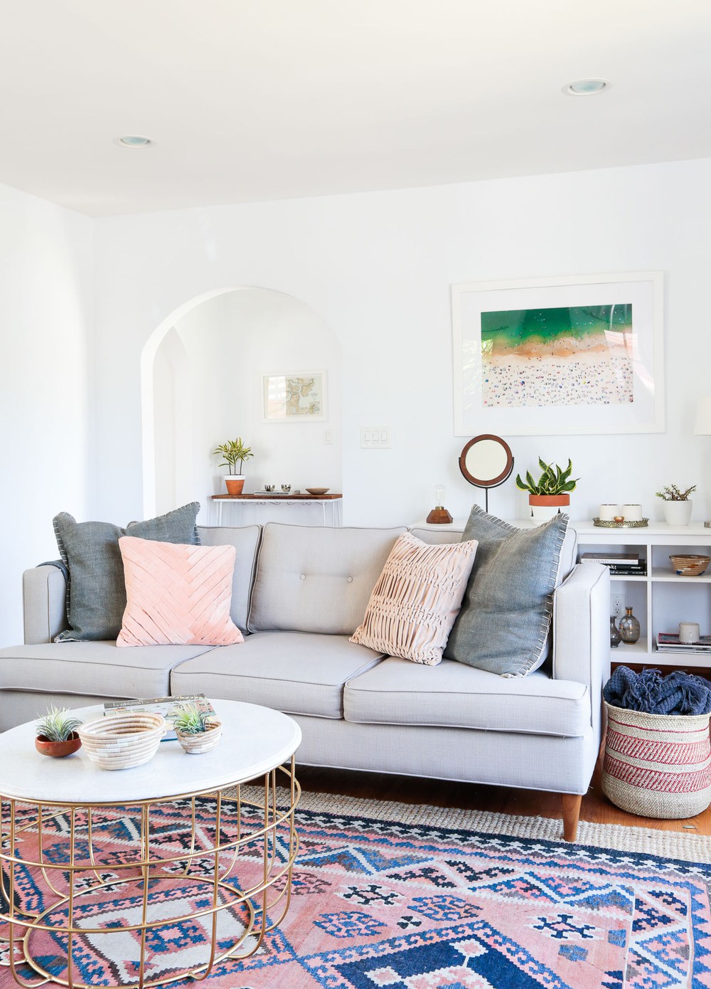 Grey sofa with pillows and pink patterned rug