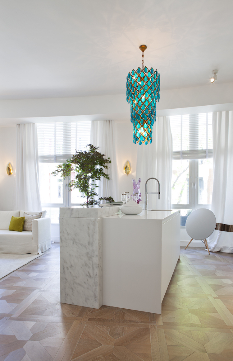 Marble island kitchen with turquoise chandelier, design by Beatriz Silveira