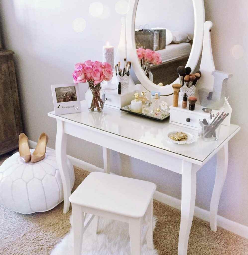 Small white vanity with pink flowers and white poof