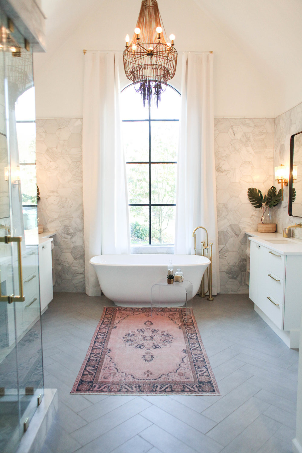 Bath with chandelier and pink rug via Redo Home and Design