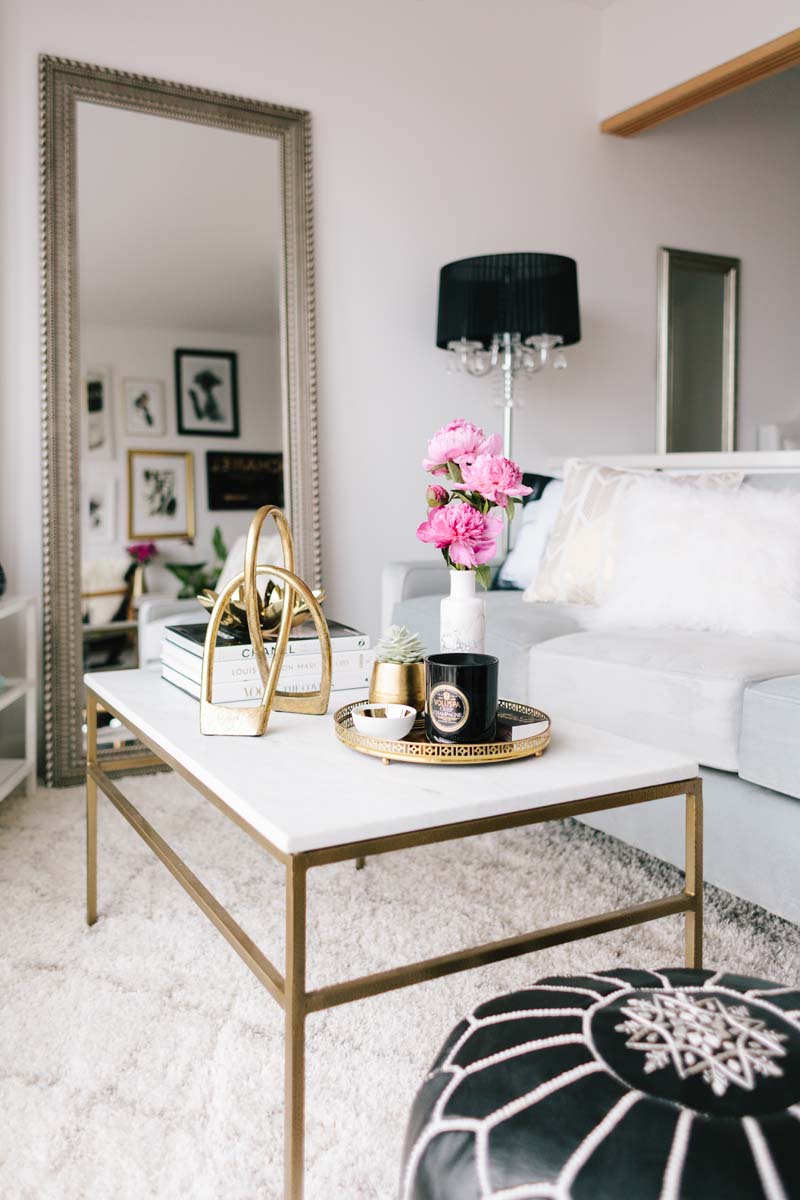 Marble coffee table with brass base and flowers via The Everygirl