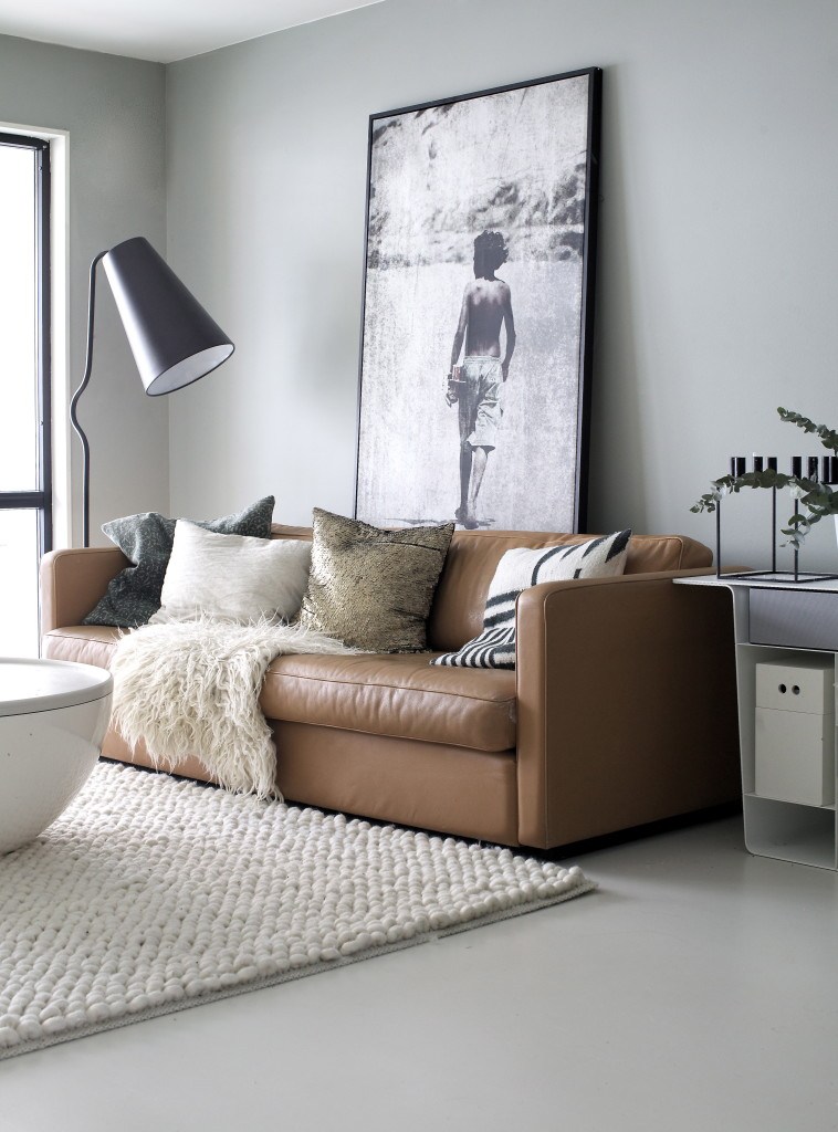 Tan leather sofa with oversized photograph and white rug