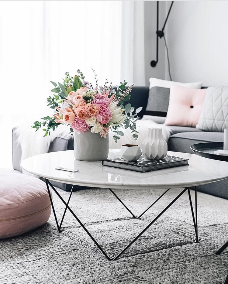 White marble coffee table with flowers and grey couch