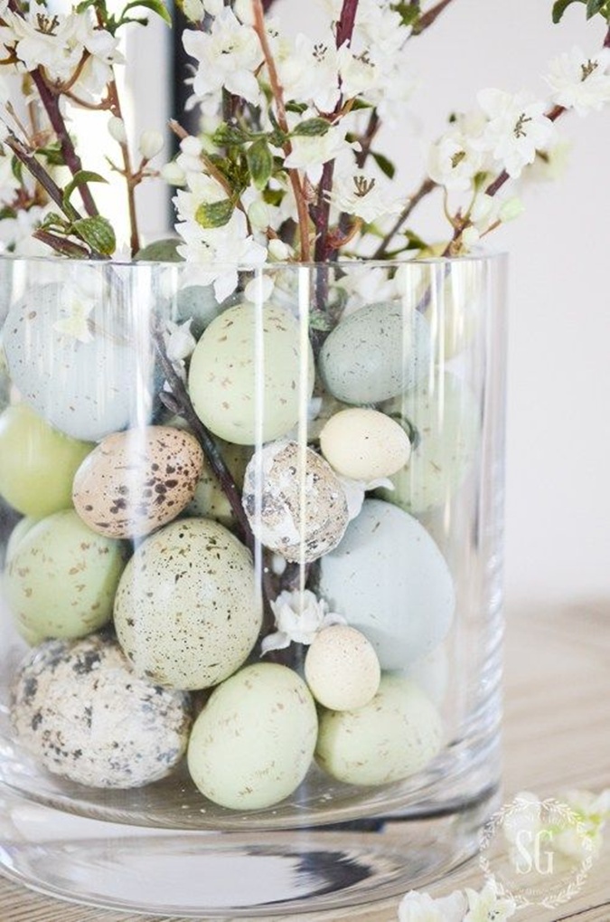 Easter eggs inside clear glass vase of flowers