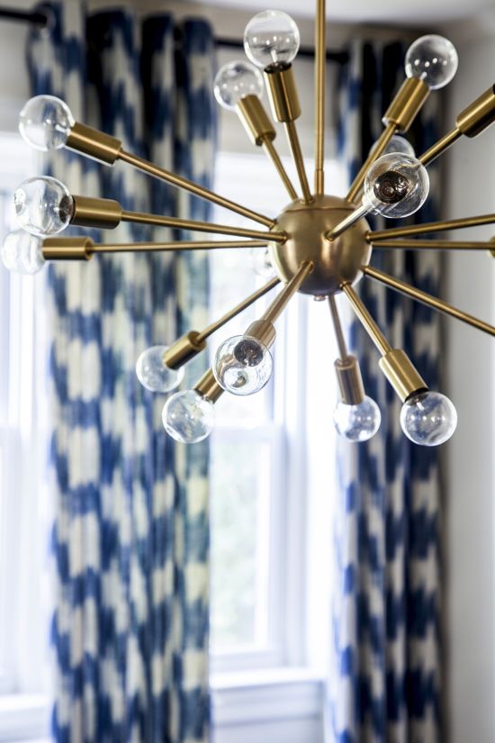 Gold starburst chandelier in front of blue curtains