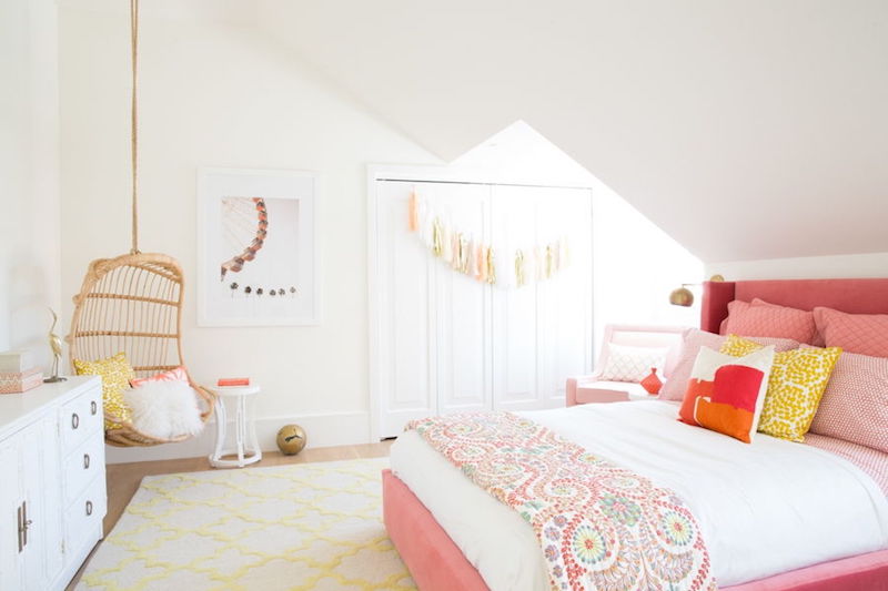 Pink bed with wicker hanging chair in corner