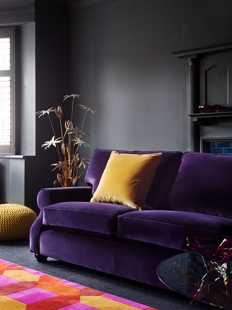 Plush purple velvet sofa with mustard yellow pillow