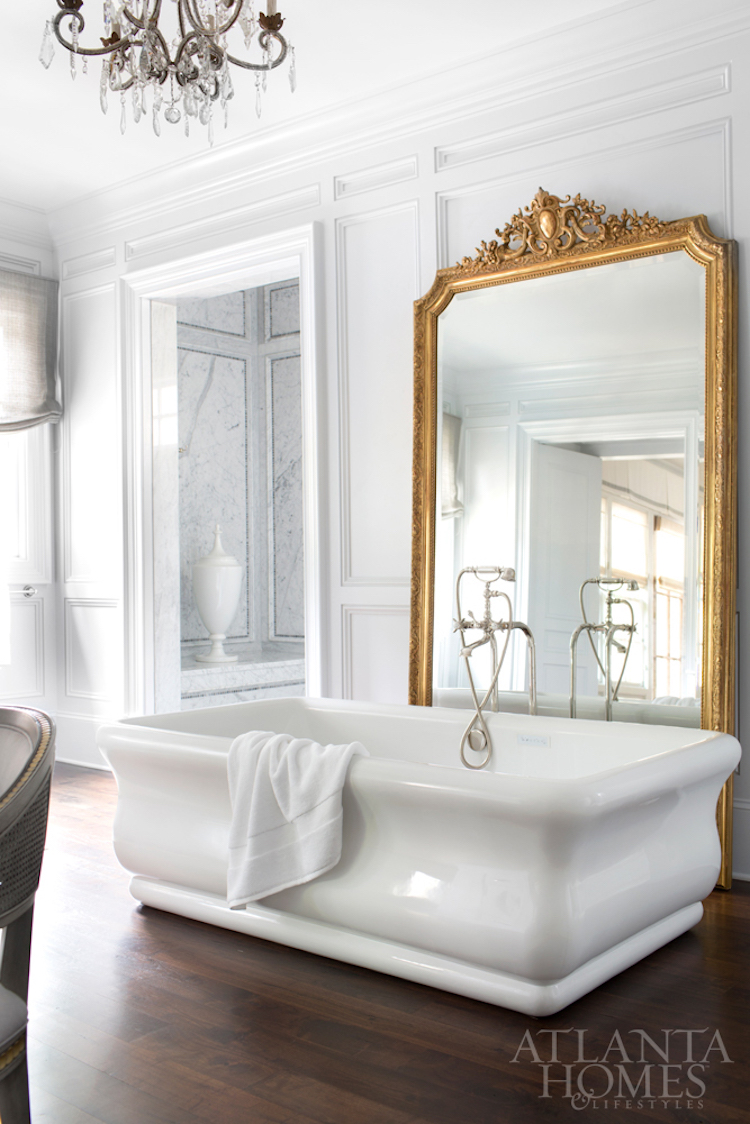 White freestanding tub with gilded mirror behind it