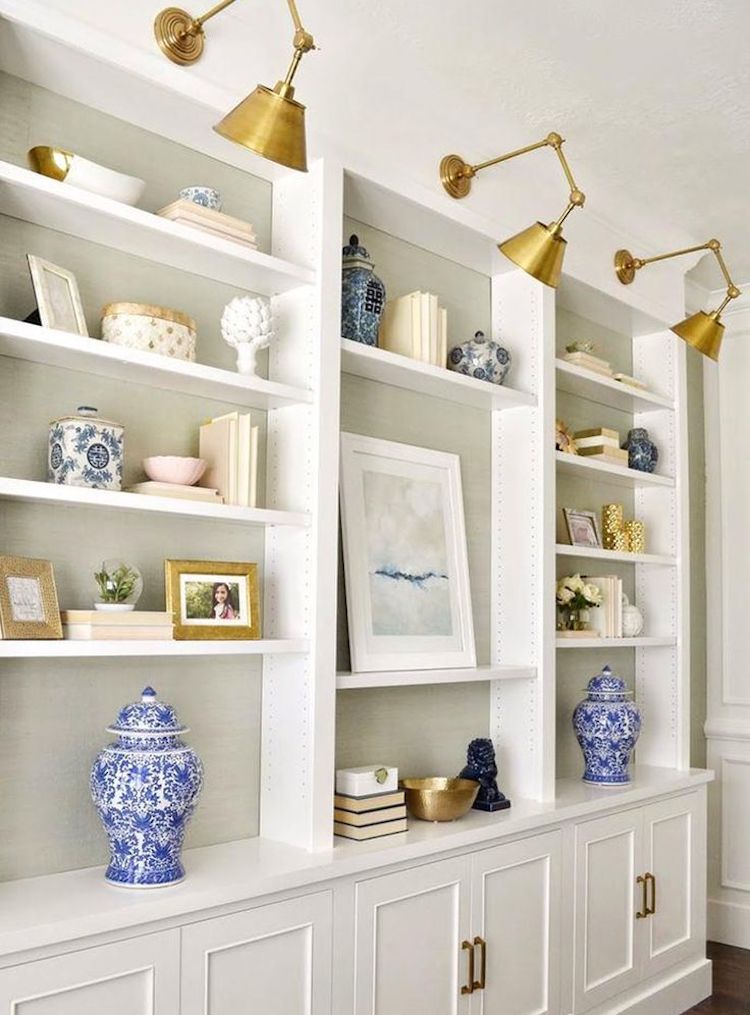 Brass swing arm sconces above bookshelf