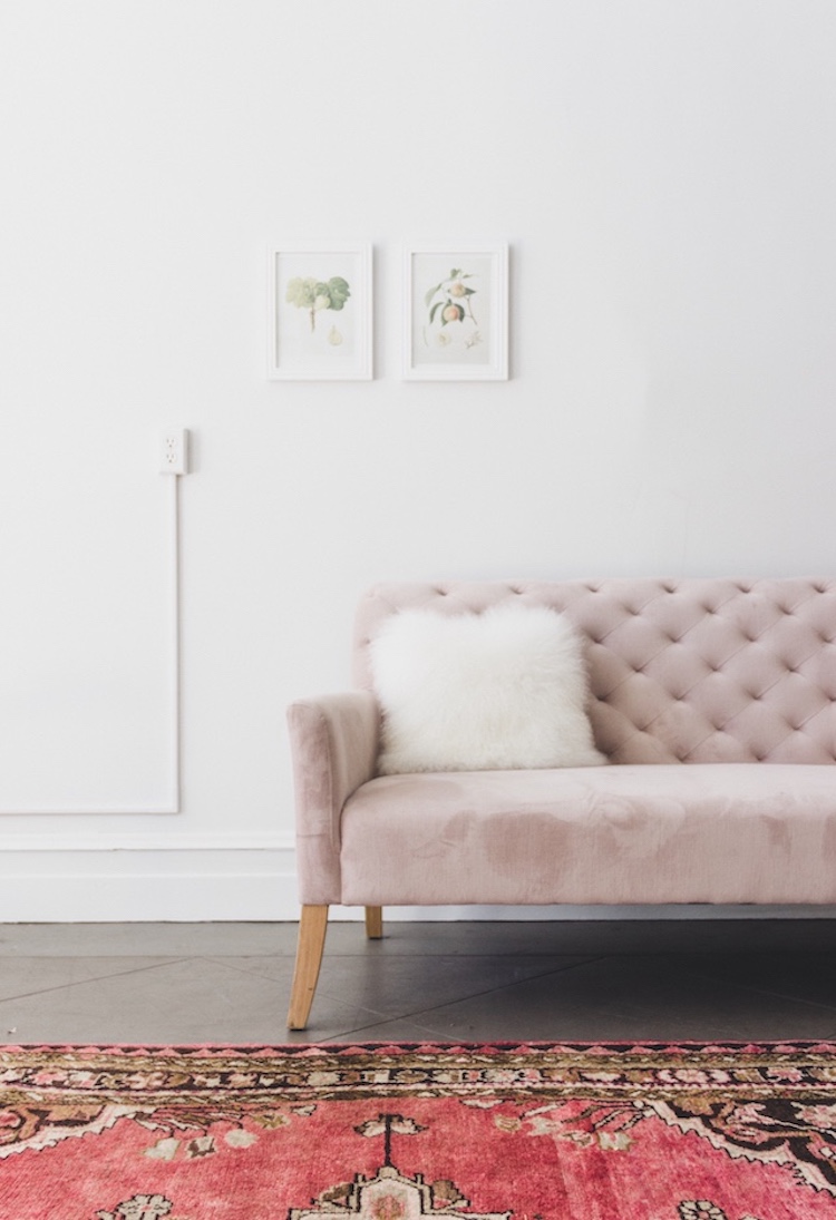 Dusty pink velvet tufted sofa with oriental rug