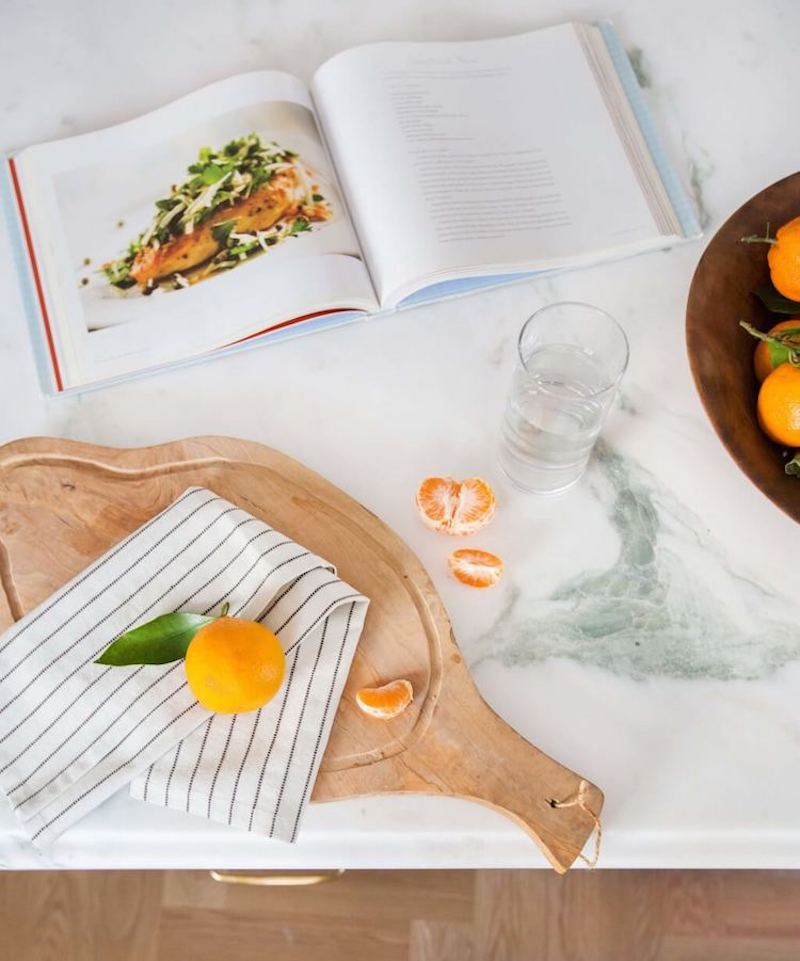 Natural wood cutting board on marble countertop via Emily Henderson