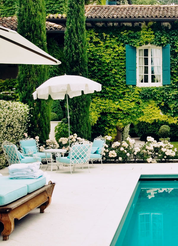 White iron outdoor chairs with blue cushions near pool