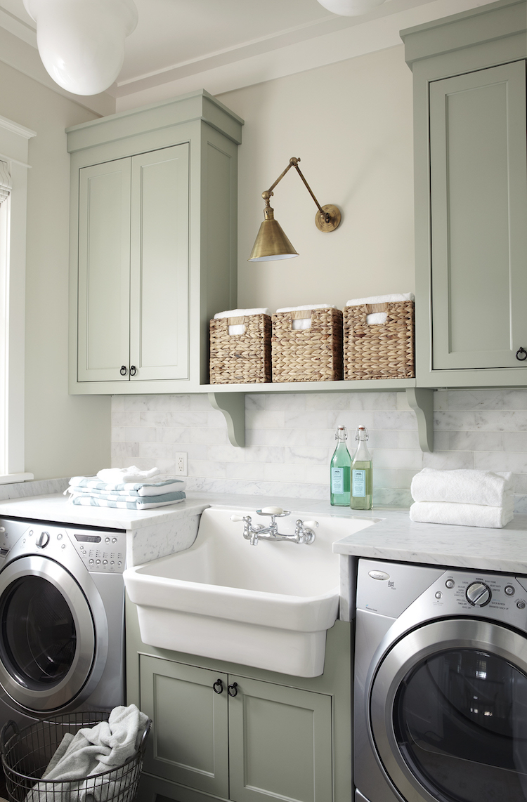 Laundry Room with green cabinets and brass sconce via Urban Grace Interiors