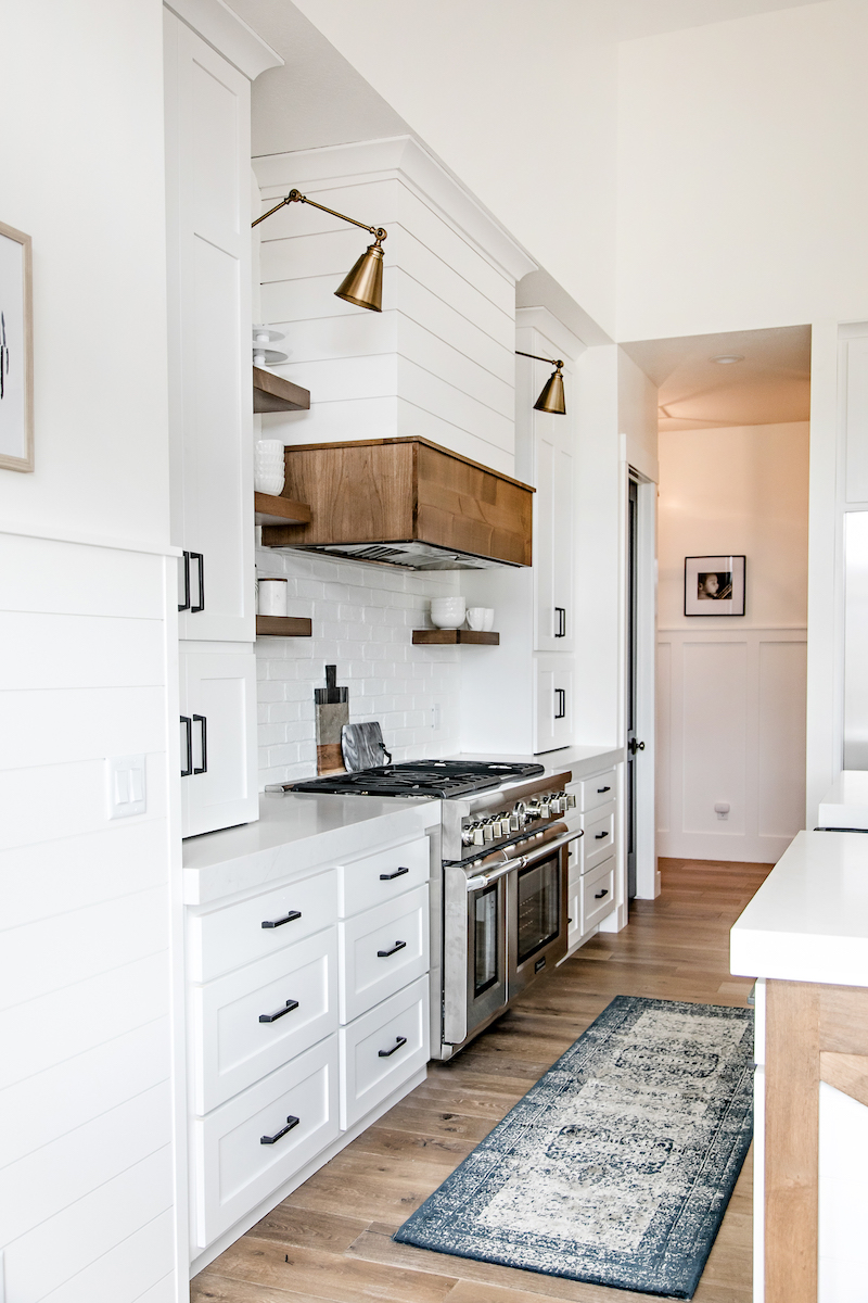 White kitchen with brass overhang sconces via Sita Montgomery