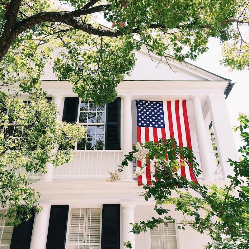 American flag hanging from large white southern style home