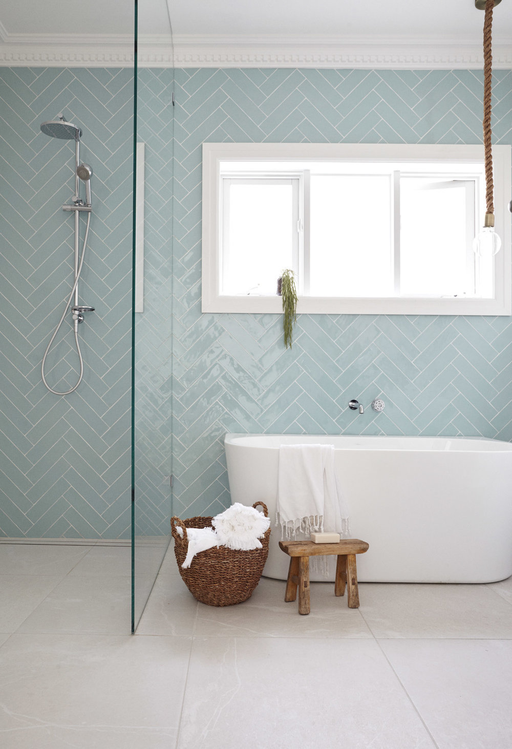 Bathroom with baby blue herringbone tiling on walls and white tub