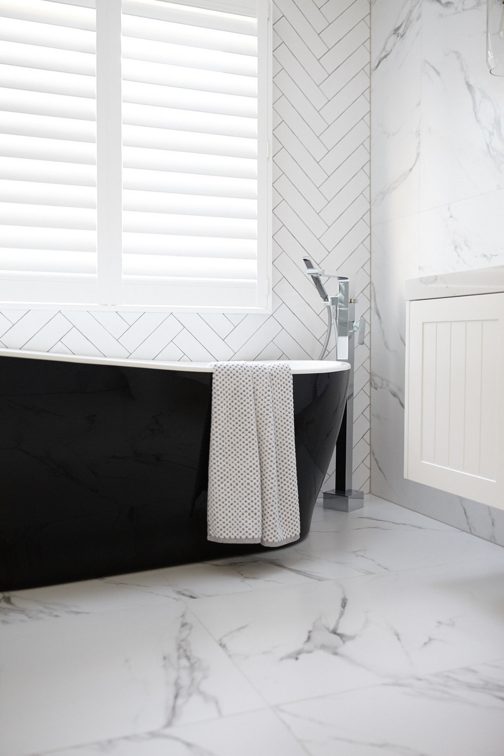 Bathroom with black tub and white marble floors