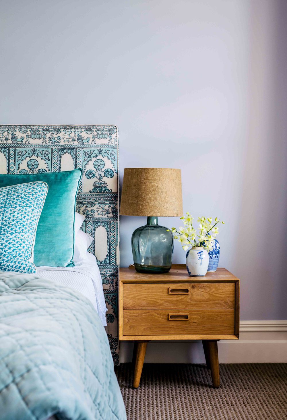 Bedroom with blue fabric headboard and mid-century nightstand