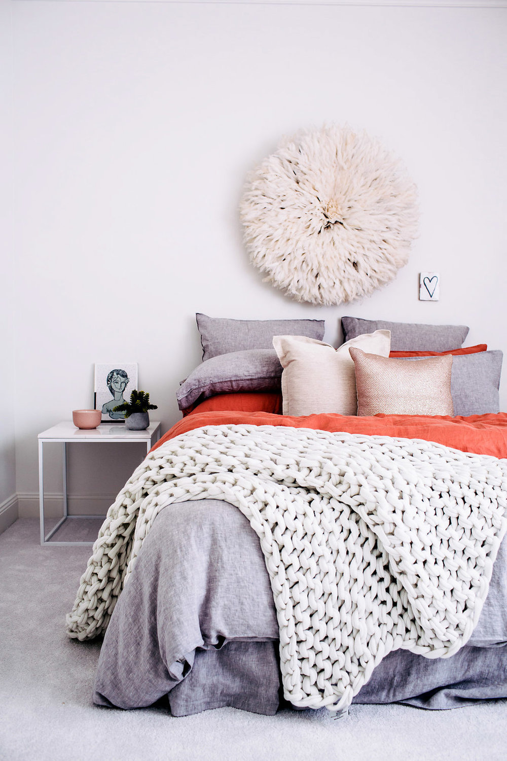 Bedroom with fur blanket and feather decor on wall