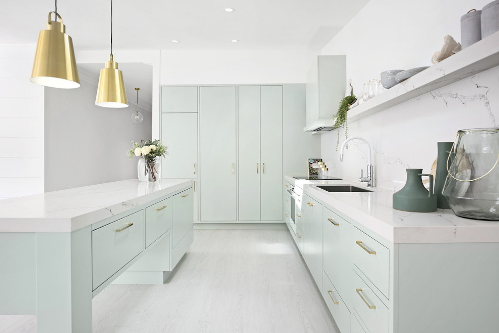 Kitchen with mint green island cabinets and two gold pendants