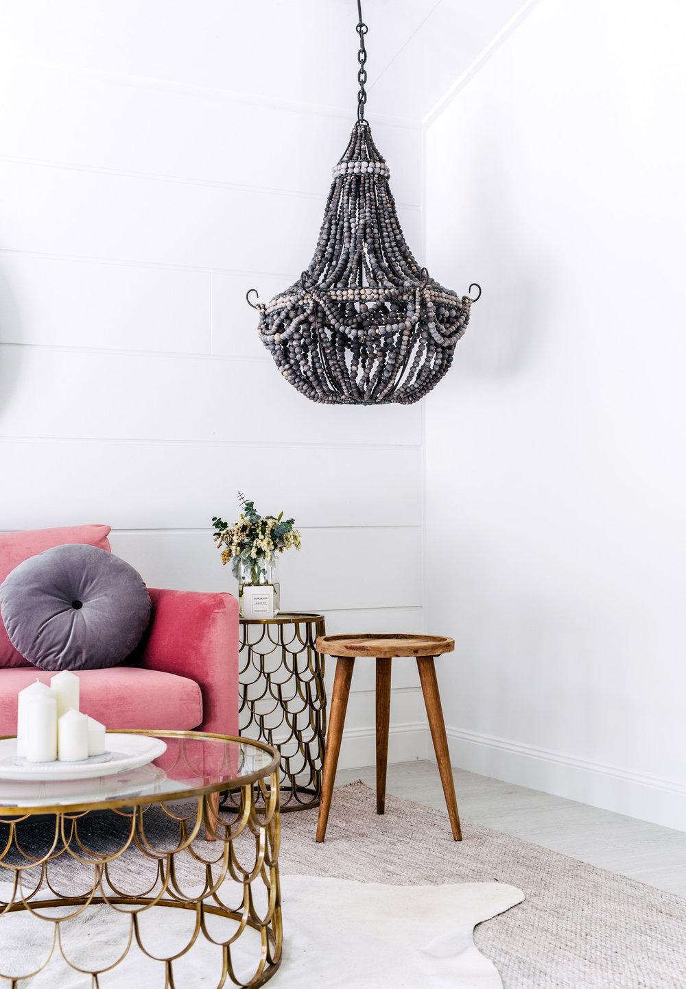 Living room by Three Birds Renovations with pink couch and black beaded chandelier