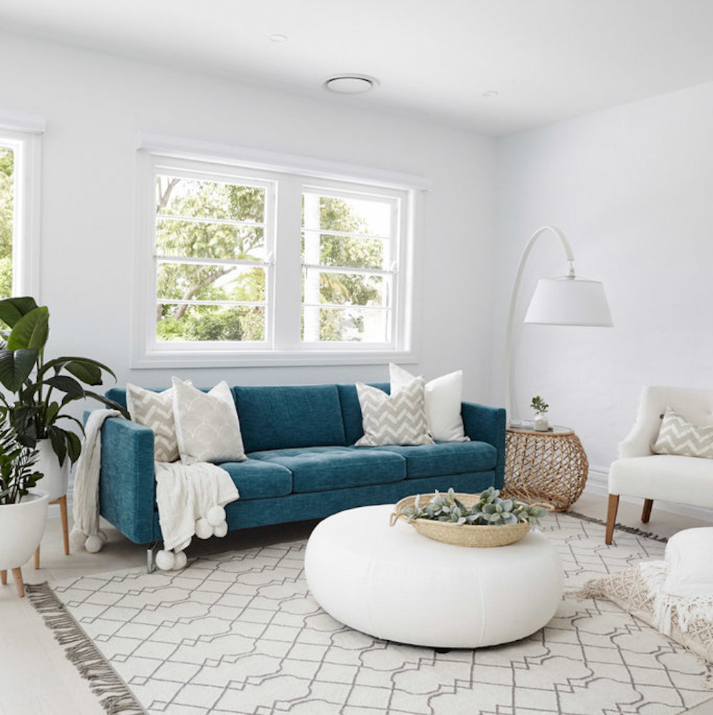 Living room with dark teal couch and neutral pillows