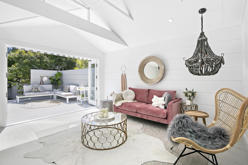 Living room with faded pink couch, beaded chandelier, and gold coffee table