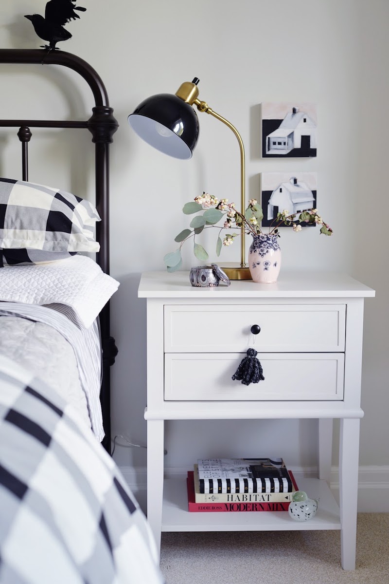 White bedside table with black task lamp in fall bedroom