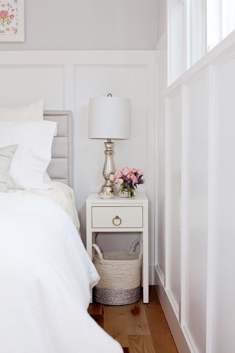 White bedside table with silver lamp and pink flowers