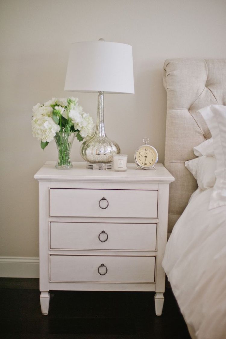 White nightstand with silver table lamp and alarm clock