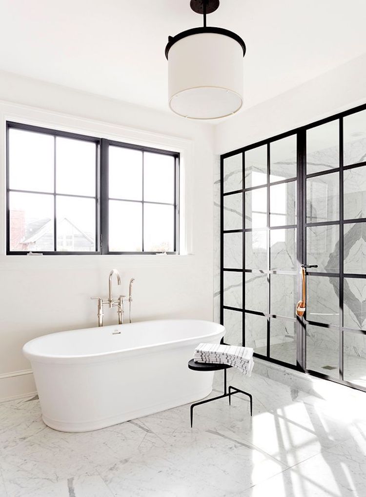 White bathtub in marble floor bathroom with black window panes via Tamara Magel