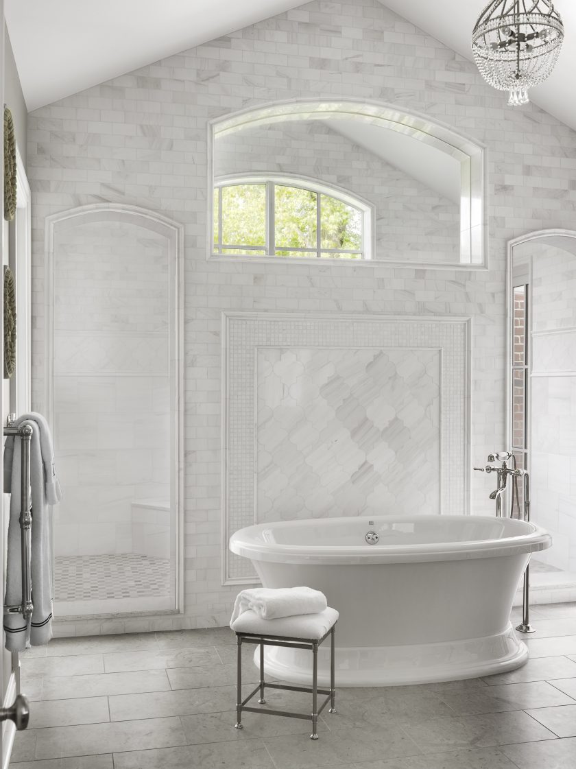 White tub in bathroom with shower and crystal chandelier via Mitchell Wall