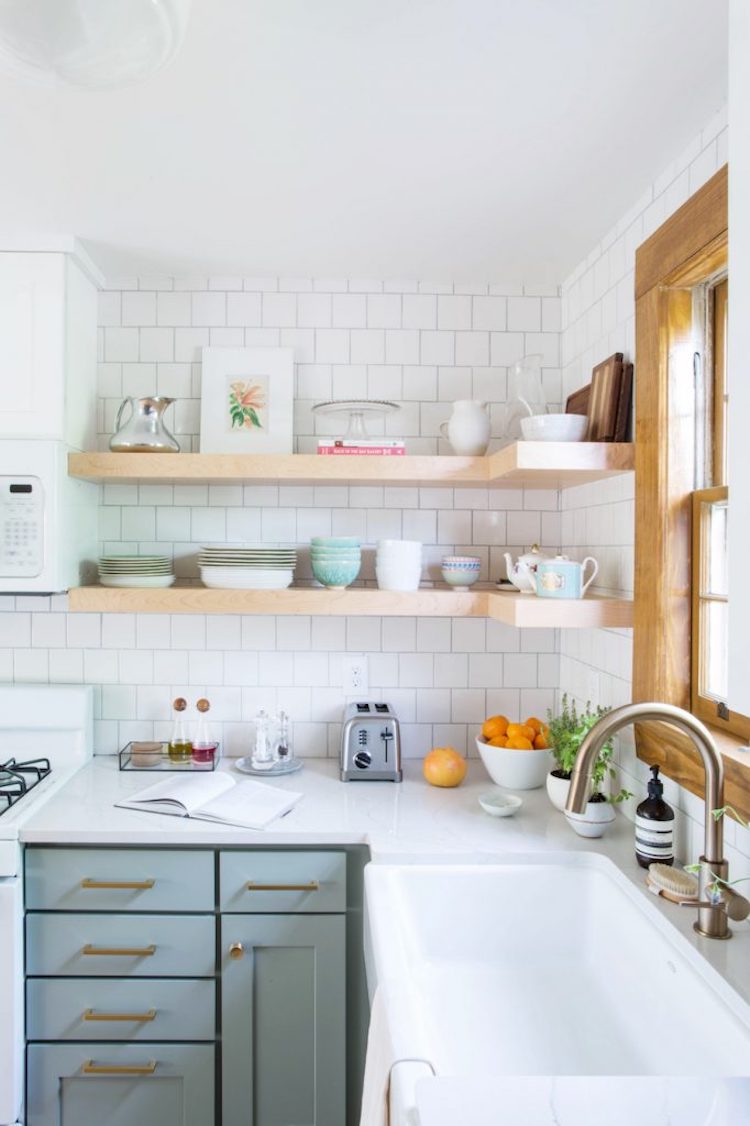 Mint green kitchen cabinets below neutral open shelves kitchen with white backsplash tiling via The Everygirl