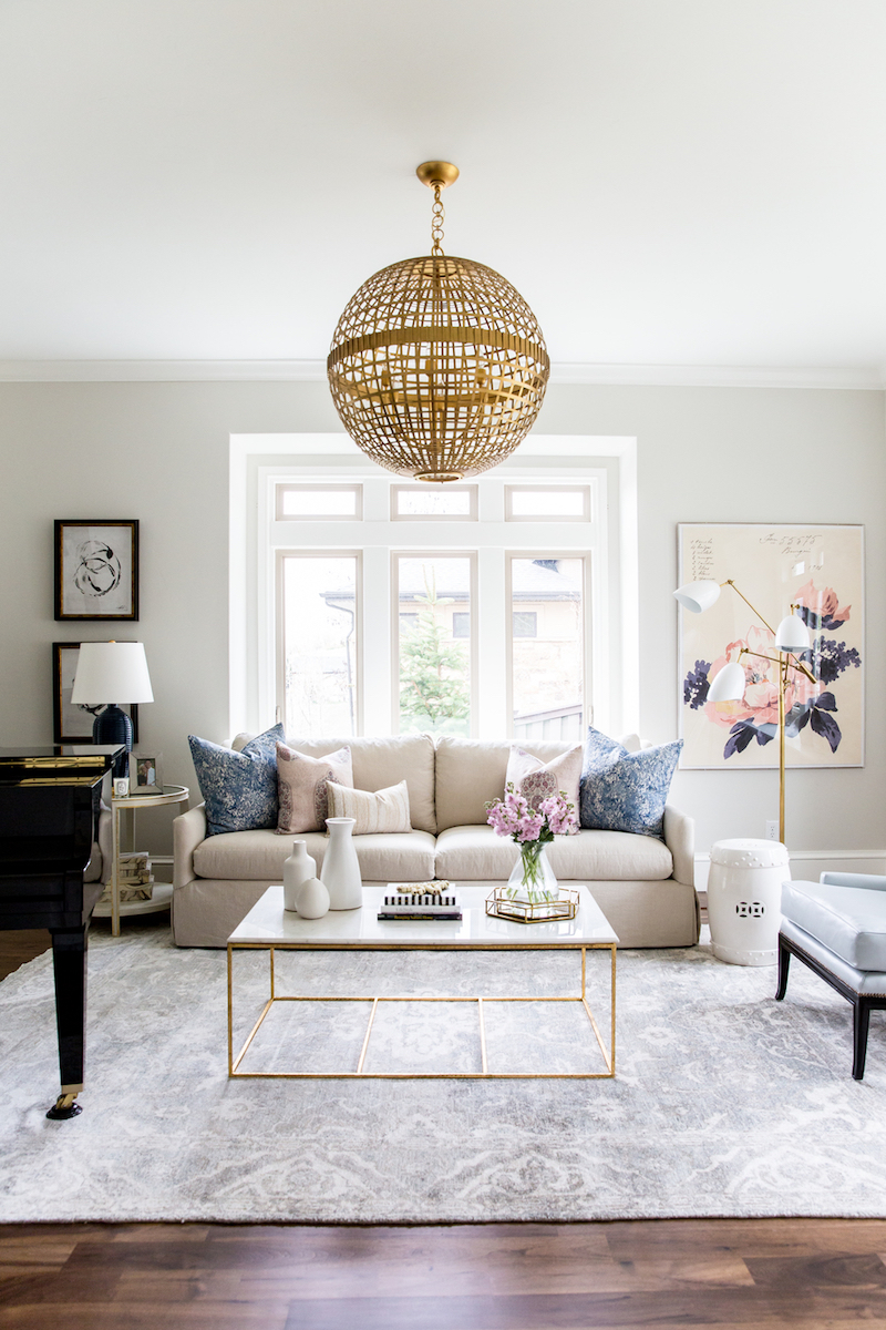 Beige couch with marble coffee table and gold chandelier via Studio McGee