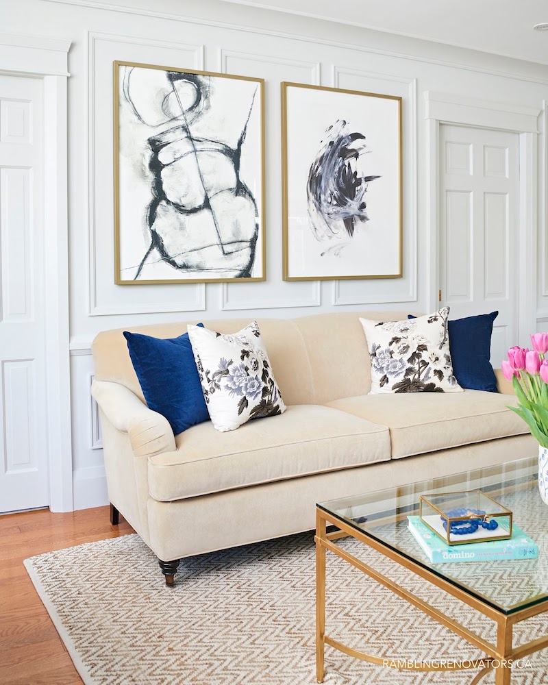 Preppy beige sofa with Navy blue and floral throw pillows in traditional living room via Rambling Renovators