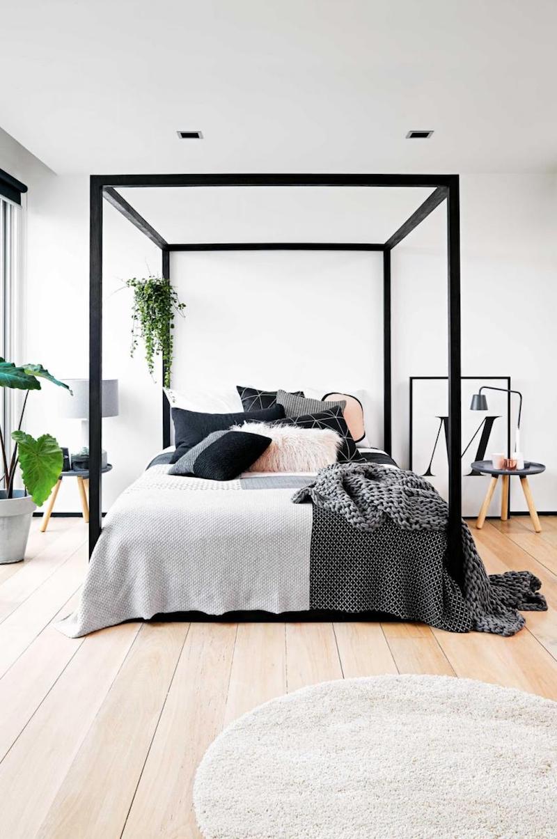 Minimal black canopy bed with grey linens in bedroom via Inside Out Mag