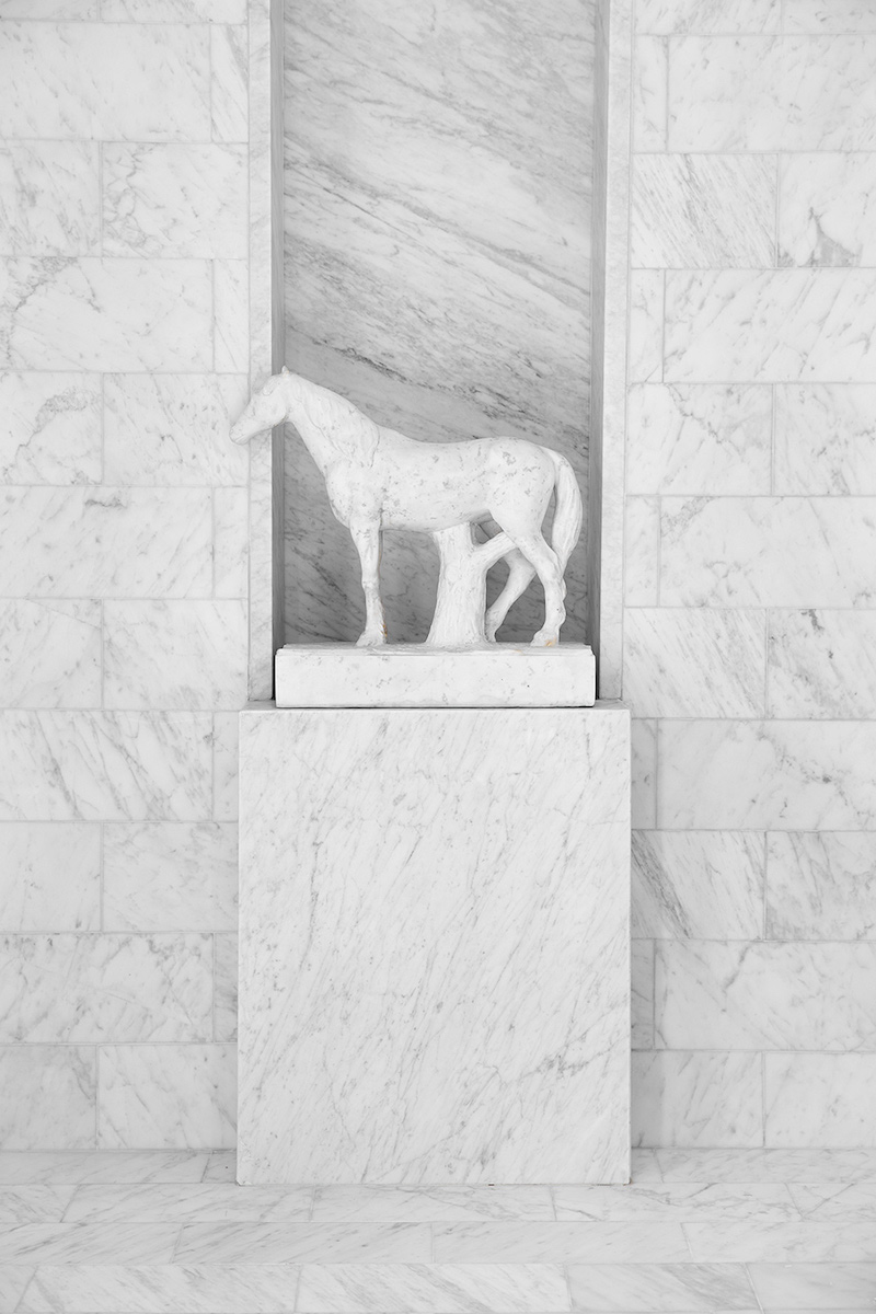 Large format tiles behind white marble horse on shower pedestal in Darryl Carter Bathroom design