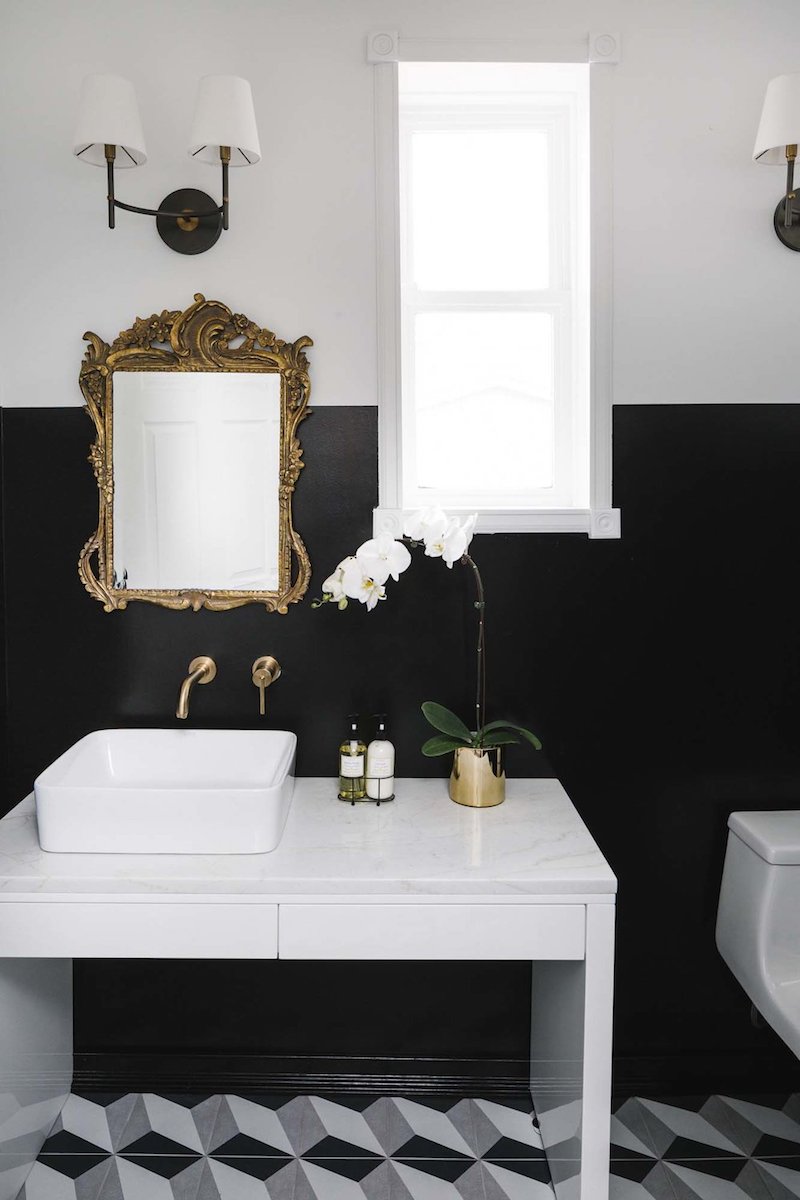 White vessel sink with brass faucet, antique gold mirror and black walls