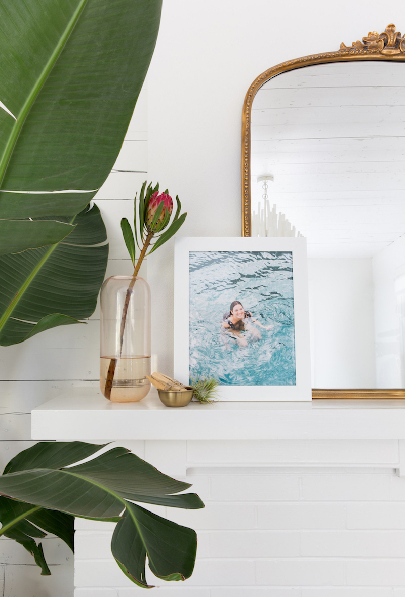 Anthro gold vintage mirror on fireplace behind artwork via Camille Styles