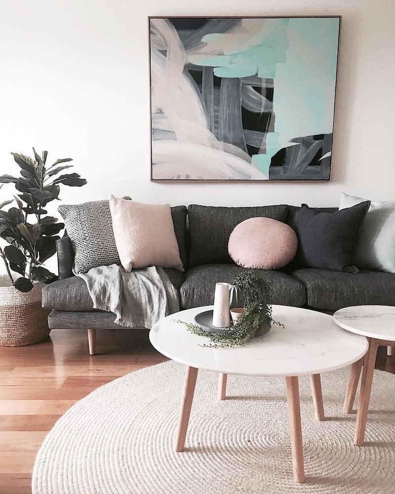 Dark grey sofa with abstract art and round white coffee table