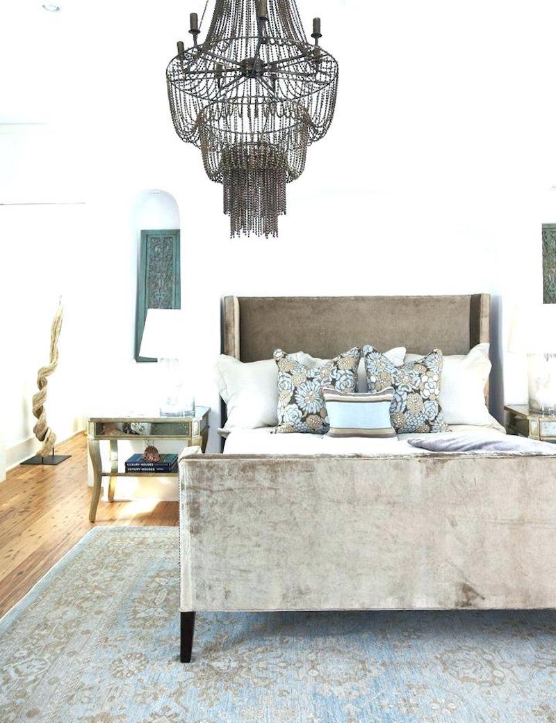 Gray velvet bed in bedroom with beaded chandelier