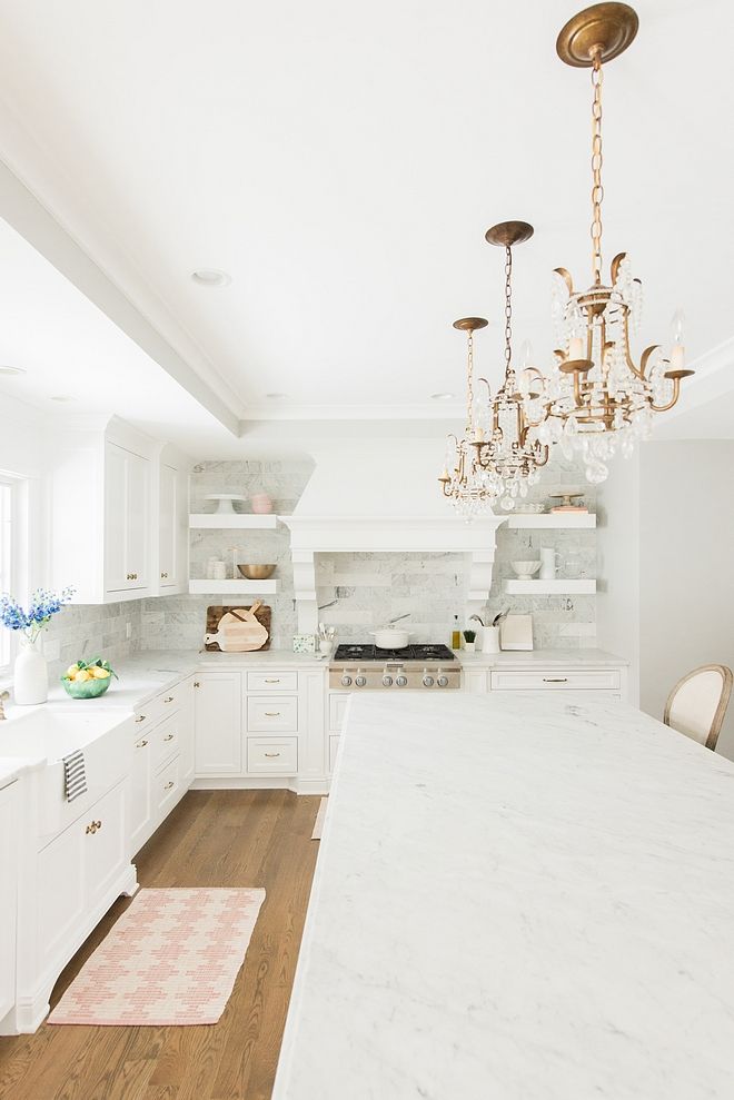 3 brass chandelier pendants above white marble kitchen island