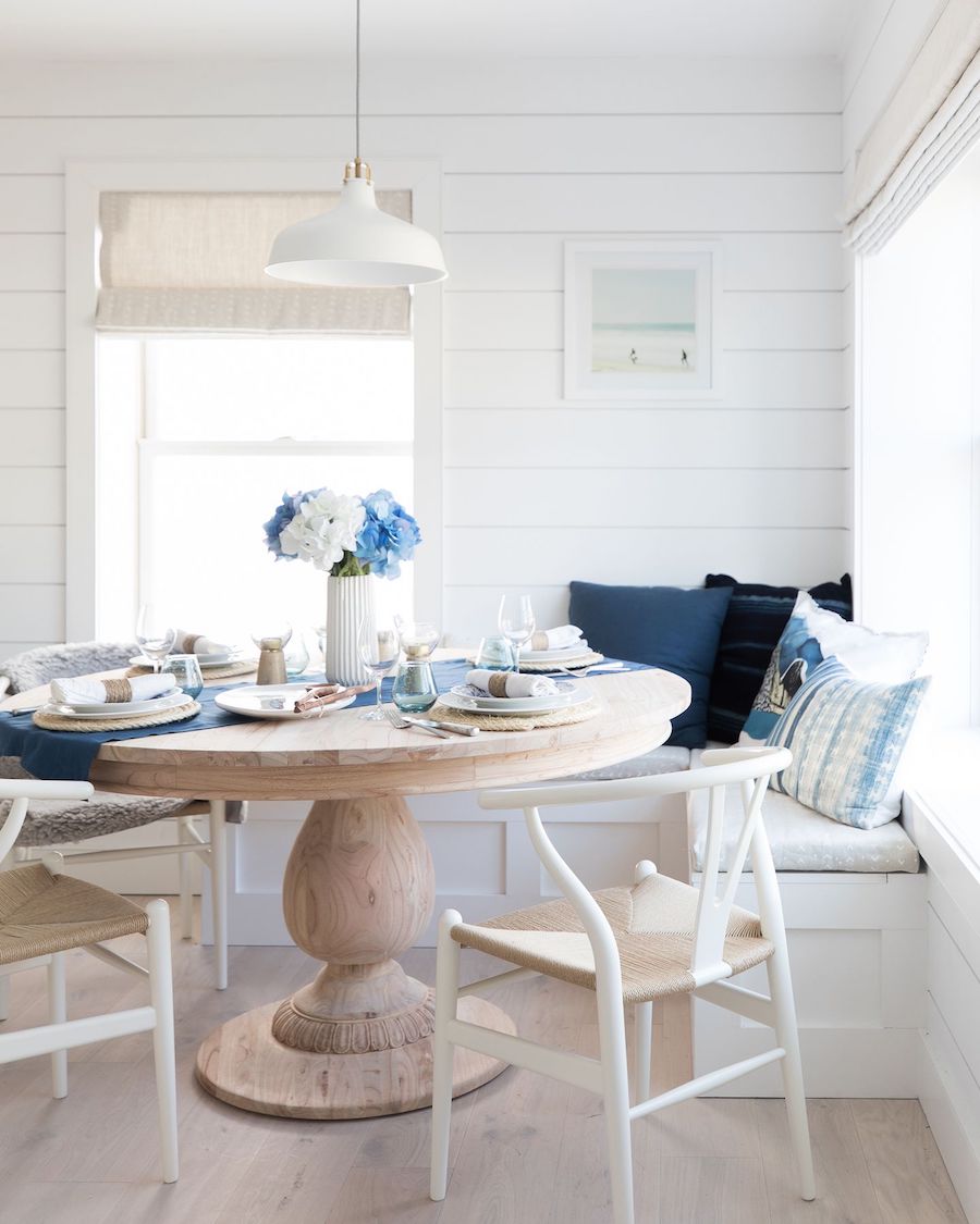 Beach home breakfast nook with wishbone chairs, shiplap walls and round dining table