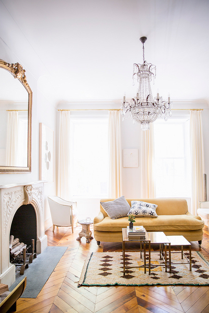 Crystal Chandelier in Living Room with Yellow Couch via Domino Brittany Ambridge