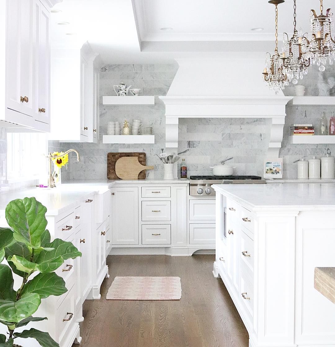 White kitchen with crystal chandelier pendants and marble subway tile