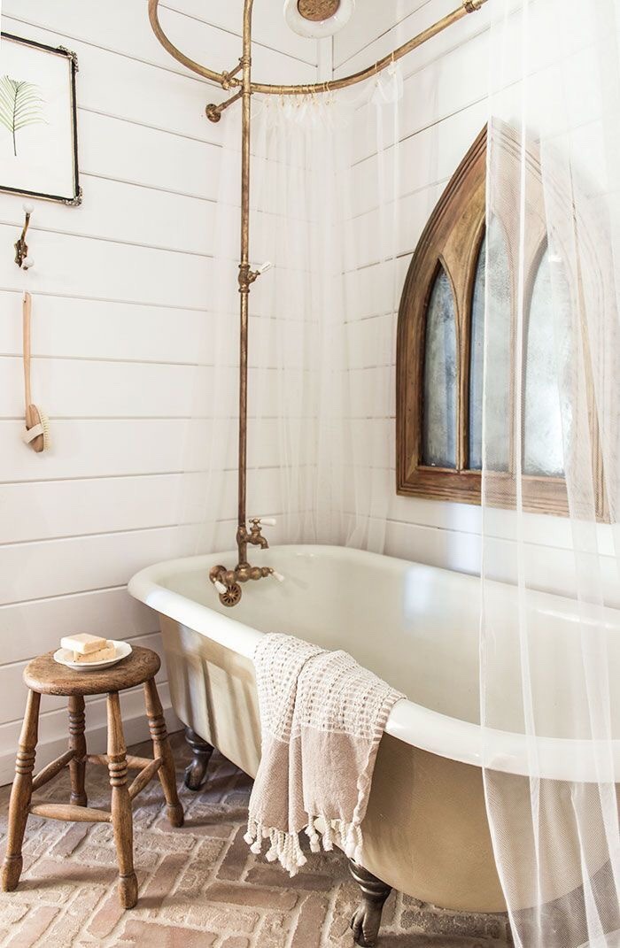 Brass shower hardware and wooden stool in Country bathroom