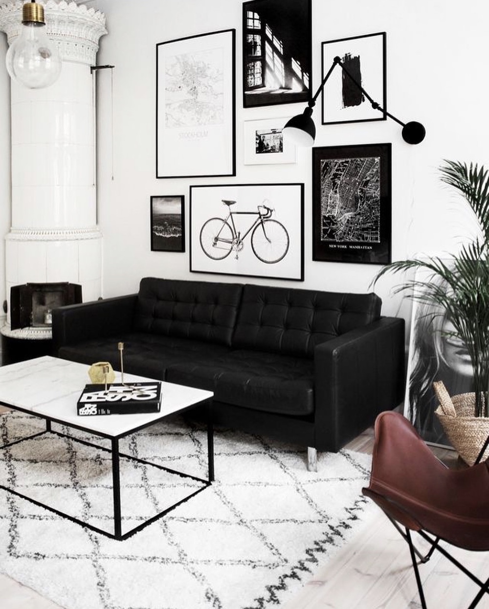 Black tufted sofa in modern contemporary living room with white marble table and gallery wall