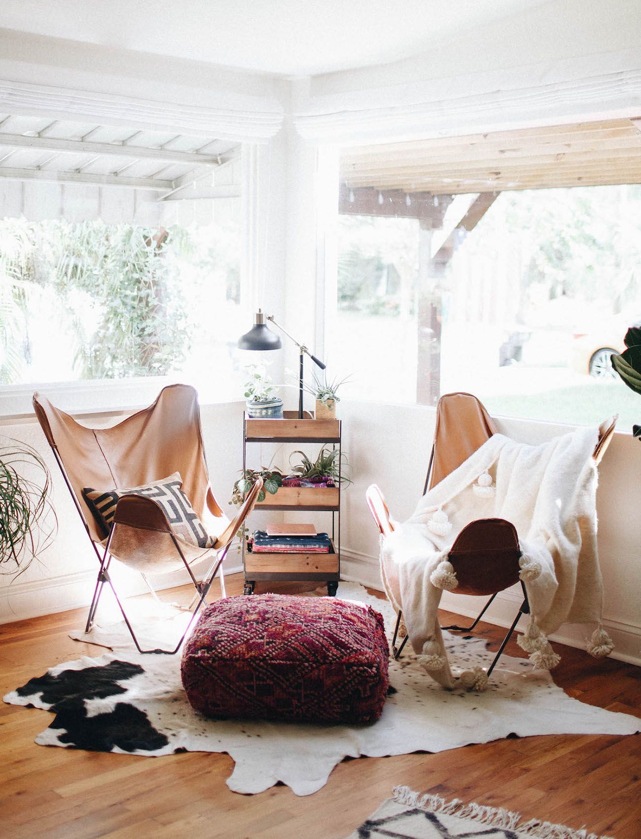 Boho seating - Leather butterfly chairs, a textile pouf ottoman, and fur throws